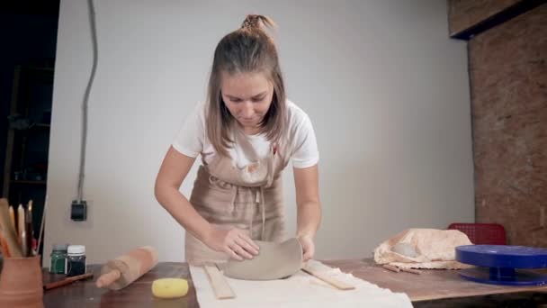 Mujer está desenrollando arcilla en la mesa utilizando rodillo en el estudio de cerámica — Vídeo de stock