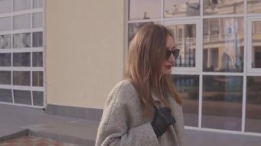 Kadın güneşli bahar gününde şehrin modern güzel binasında yürüyor.