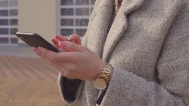 Vrouw in overjas met smartphone. — Stockvideo