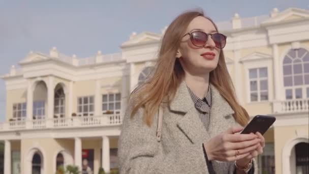 Mujer bonita está respondiendo en SMS por teléfono inteligente, al aire libre en la calle de la ciudad — Vídeo de stock