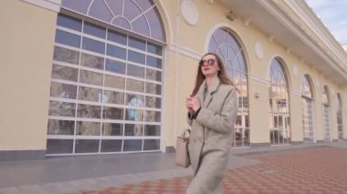 İş kadını güneşli sonbahar gününde güzel binanın yakınında bahçede adım atıyor