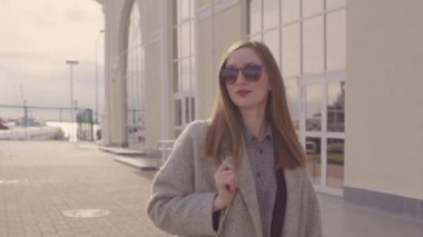 Gülümseyen genç kadın güneşli bahar gününde şehirde sokakta yürüyor