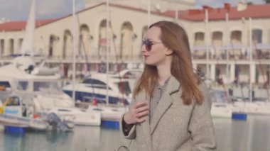 Kadın, güneşli bahar gününde şehir limanında rıhtımda yürüyor. Yakın plan.