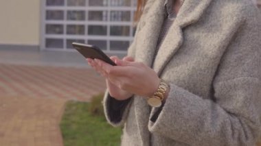 Genç iş kadını, baharda açık havada akıllı telefonuyla SMS yazıyor.