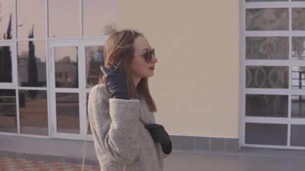 Stylish young woman takes a walk in a spring city. — Stock Video