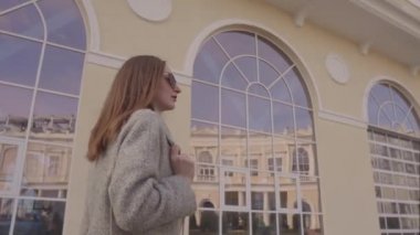 Kendine güvenen zengin kadın bahar gününde şehirdeki güzel binanın yakınında yürüyor