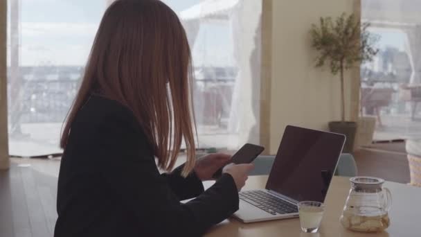 Mujer usando smartphone y laptop en restaurante . — Vídeos de Stock