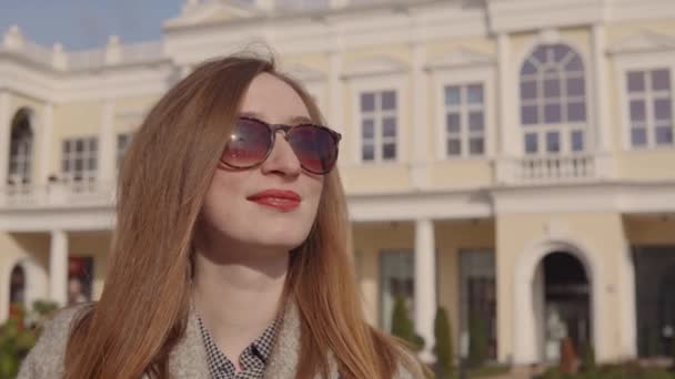 Η χαρούμενη γυναίκα-κοκκινομάλλα χαμογελάει, στέκεται έξω στην ηλιόλουστη μέρα της άνοιξης — Αρχείο Βίντεο