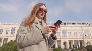 Neşeli kadın fotoğrafları görüntüleyip cep telefonuyla sms okuyor