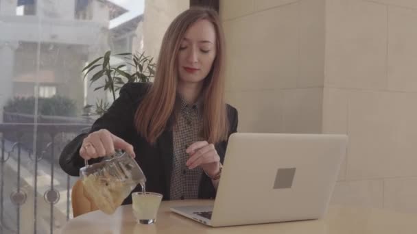 Žena pije čaj a pracuje na PC