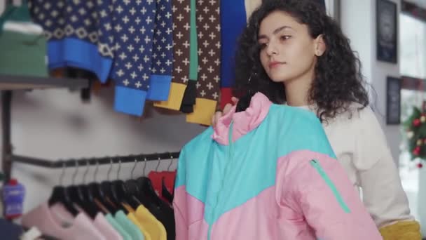 Chica eligiendo entre dos piezas de tela en una tienda . — Vídeos de Stock