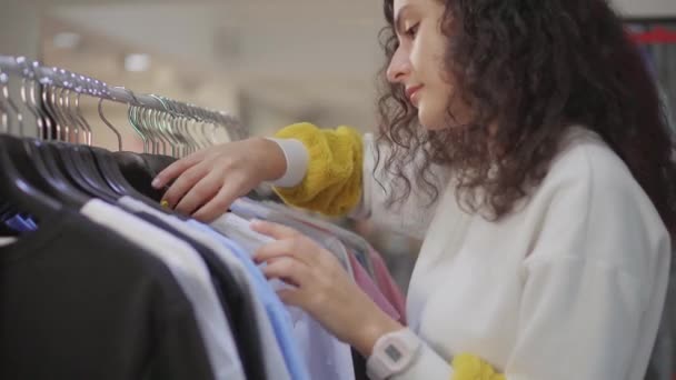 Jonge vrouwelijke klant die kleding kiest. — Stockvideo