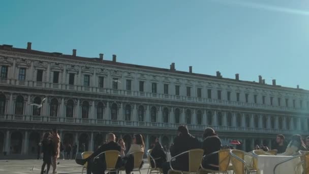 Italia, Venezia - febbraio 2019: I turisti riposano in un caffè in Piazza San Marco nella soleggiata giornata invernale — Video Stock