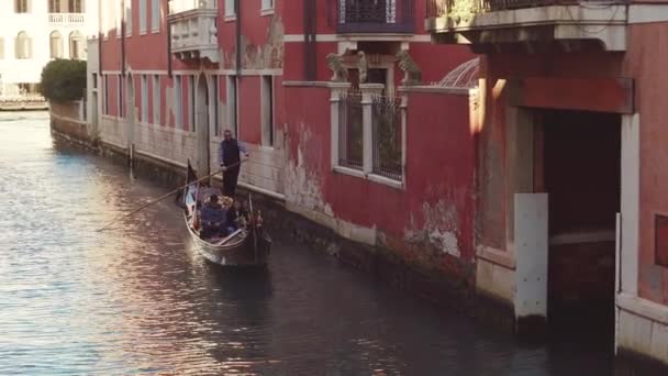 Italia, Venetsia - helmikuu, 2019: Gondolier ajaa perinteistä gondolia matkailijoiden kanssa — kuvapankkivideo