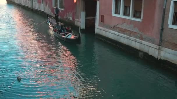 Itália, Veneza - Fevereiro de 2019: Os turistas estão andando de gôndola sobre um pequeno canal veneziano — Vídeo de Stock