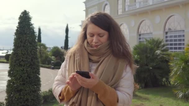 Mujer elegante con un teléfono inteligente al aire libre . — Vídeo de stock