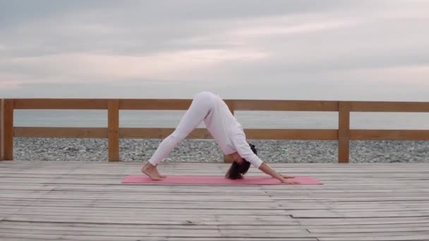 Flexibel kvinna gör yoga på frisk luft till sjöss. — Stockvideo