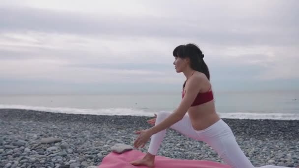 Entrenamiento de mujer flexible en una playa . — Vídeo de stock