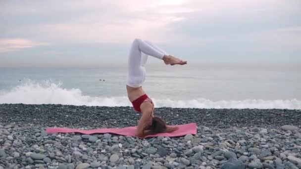 Спортивная девушка делает стойку на голове на пляже . — стоковое видео