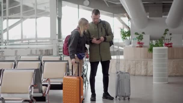 Couple of tourists are walking over hall of airport, carrying suitcases — Stock Video