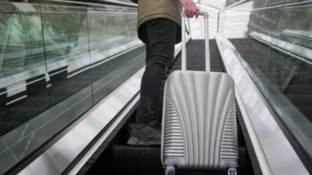 El hombre con la maleta están de pie en la escalera mecánica en movimiento, vista de cerca de las piernas — Vídeos de Stock