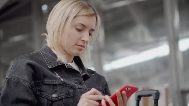 Passageiro feminino está digitando no smartphone na sala de espera, vista em seu rosto — Vídeo de Stock