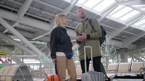Cestovatelé stojí uvnitř velké čekárny na letišti, muži a ženy — Stock video