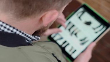 Adam tablet ile online ayakkabı mağazası sitesi inceliyor, omuz yoluyla görünümü