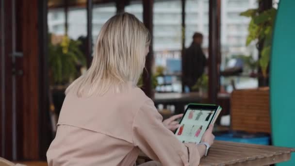 Женщина посетитель кафе сидит на открытом воздухе и покупки онлайн по планшету — стоковое видео