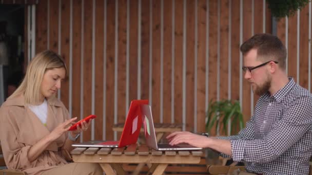 Zwei männliche und weibliche Besucher des Straßencafés arbeiten mit Laptops — Stockvideo