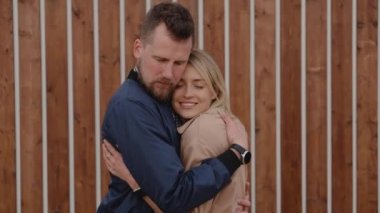 Aşıklar açık havada şefkatle sarılırlar, birbirlerine sevgiyle bakarlar.