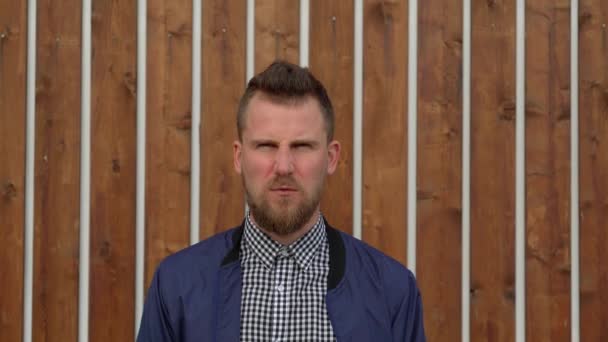 Angry young man is shouting and screaming, waving hands outdoor, medium shot — Stock Video