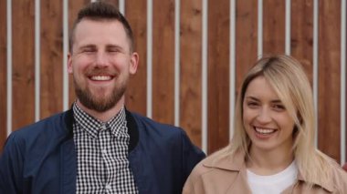 Mutlu aile çifti gülüyor ve kamera açık havada, orta çekim bakıyor