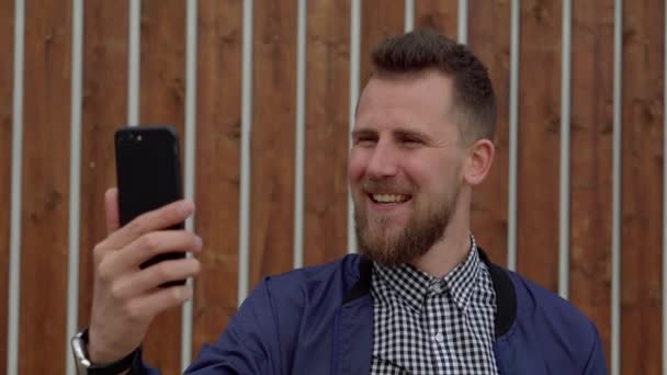 Chico guapo alegre está hablando por teléfono móvil usando videollamada — Vídeo de stock