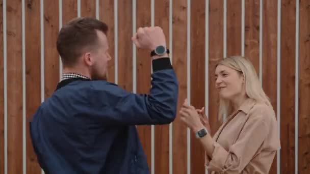 Δύο νεαροί άνδρες και γυναίκες χορεύουν σε εξωτερικούς χώρους κοντά σε ξύλινο τοίχο — Αρχείο Βίντεο