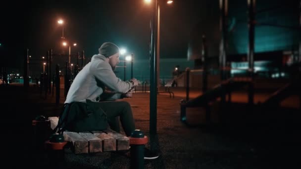 Athlete is relaxing after training in sports ground, drinking water from bottle — Stock Video