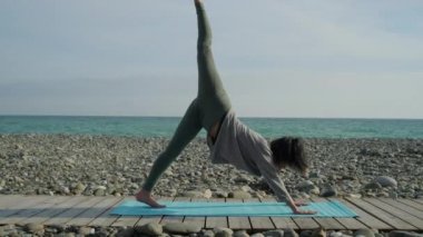 Kız tek başına plaj kıyısında Yoga pratik.