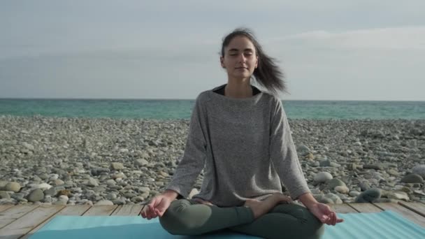 Chica joven relajándose en una playa meditando . — Vídeos de Stock