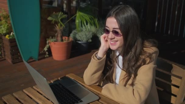 Lächelndes Mädchen in stilvoller Kleidung mit Laptop. — Stockvideo