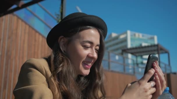 Чарівна дівчина в соціальних мережах через смартфон на відкритому повітрі . — стокове відео