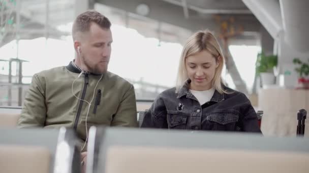 Férfi és nő ül a repülőtéren közel. — Stock videók