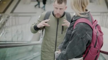 Havaalanında yürüyen merdiven üzerinde iki yolcu.