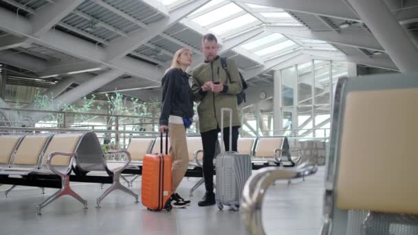 Guy causaly talking to woman in airport. — Stock Video