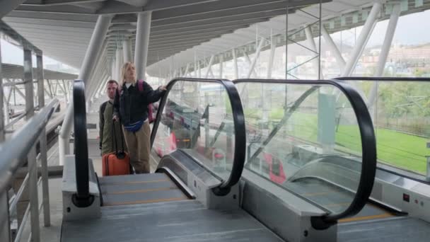 Casal viajante na escada rolante do aeroporto com bagagem . — Vídeo de Stock