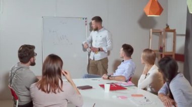 Ofis çalışanlarının önünde sunum yapan müdür.