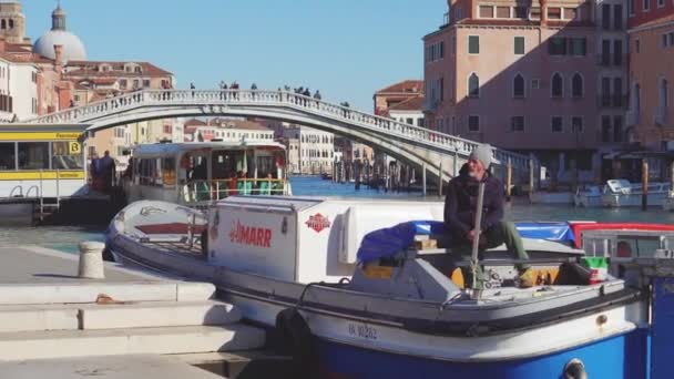 Itália, Veneza, fevereiro de 2019. Velho sentado em um barco estacionado e desfrutando de um dia ensolarado quente . — Vídeo de Stock