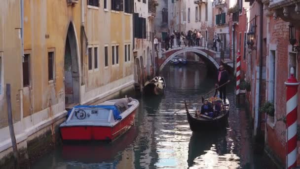 Italia, Venecia, febrero de 2019. Gondolier remando un barco con al turista en romántico paseo acuático en una ciudad . — Vídeos de Stock