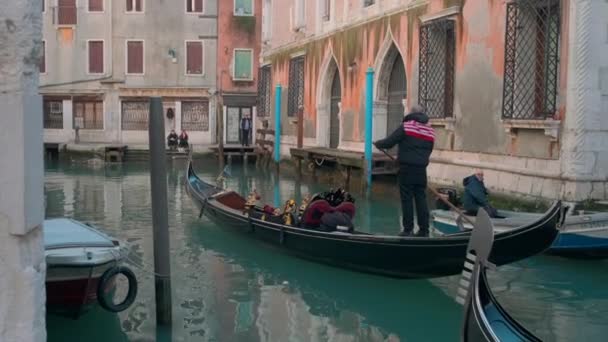 Italien, Venedig, februari 2019. Sido utsikt skott av en ensam gondoljär rodd en tom båt i en smal gatu kanal i Venedig. — Stockvideo