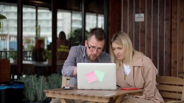 Пара, использующая один ноутбук за столом кафе . — стоковое видео