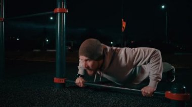 Sakallı adam spor sahasında itiş yapıyor.